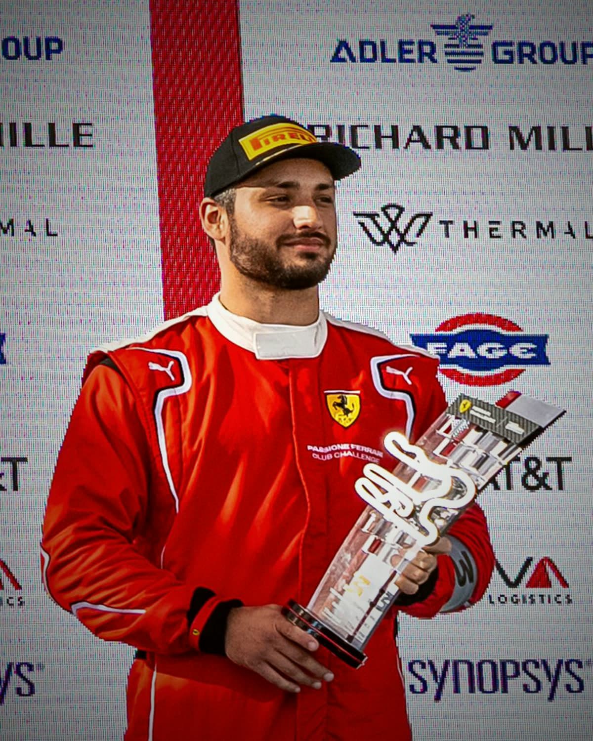 Kevin Gutiérrez in his Ferrari race suit holding a trophy on the Ferrari Challenge podium